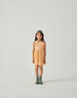 Campaign photo of the Emily Ruffled Apron Dress with Botanical Embroidery for kids from the Spring Summer collection of Filipino kids fashion brand Gingersnaps Philippines, featuring yellow gingham fabric, botanical embroidery, and wide apron straps.