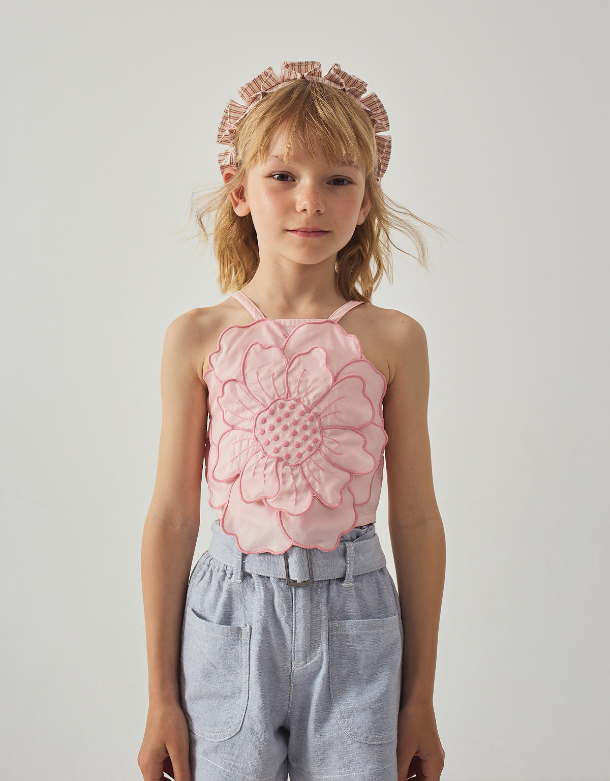 Stylized catalog shot of a child wearing the Eloise Halter Top in Pink with Large Flower Appliqué & Contrast Stitching from the Spring Summer collection of Filipino kids fashion brand Gingersnaps Philippines, styled as a standout summer piece.